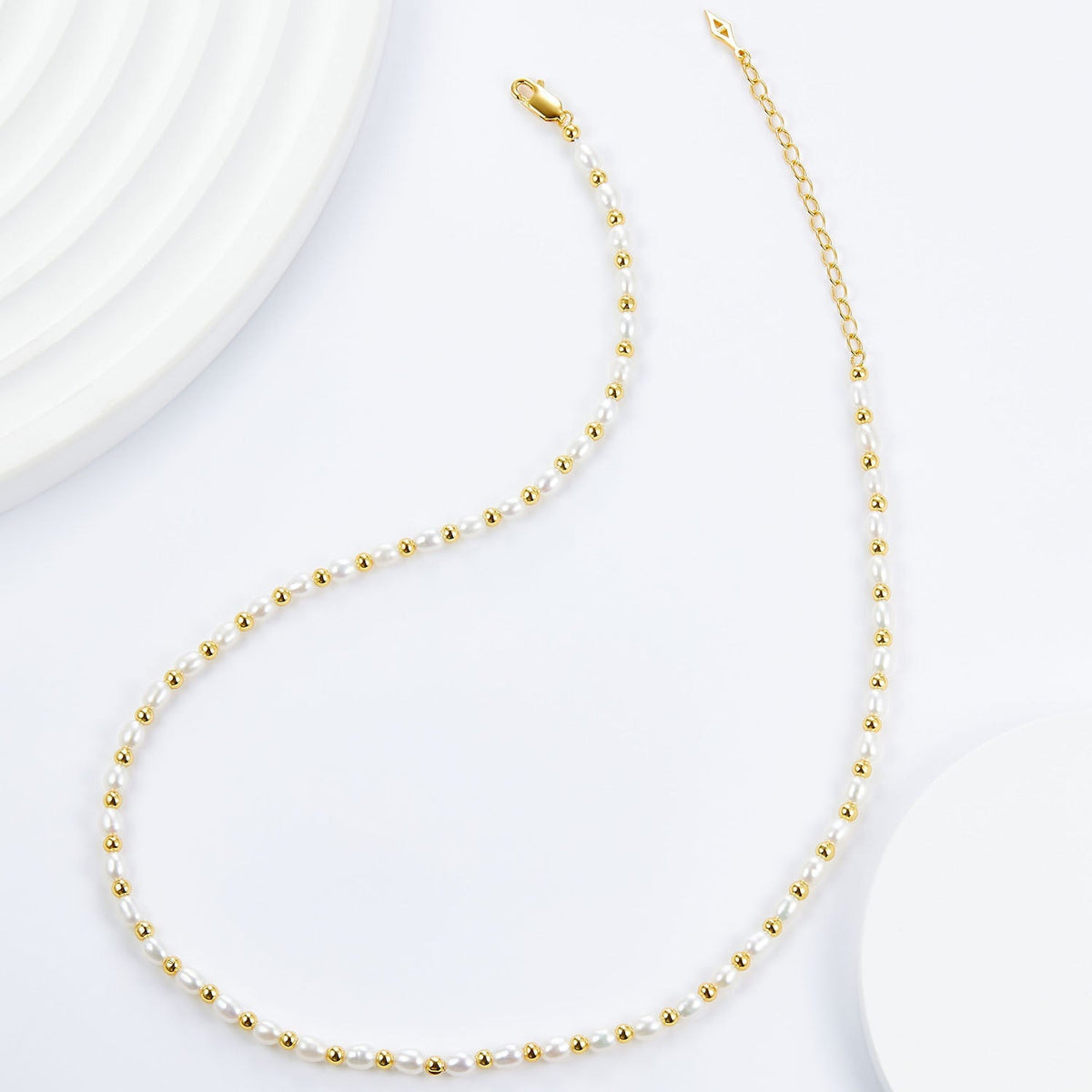 Overhead view showing the complete Bare Luxe Golden Pearl Necklace layout with gold chain and clasp.