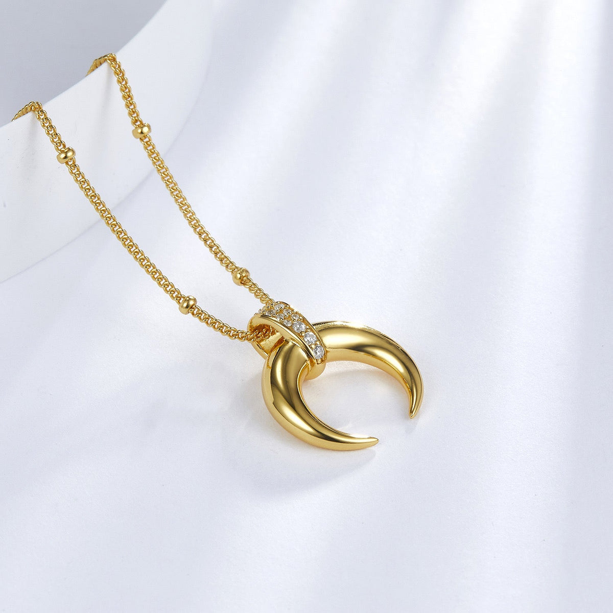 Angled detail view of the Awakened Time gold Radiant Horn pendant with sparkling gem bail.