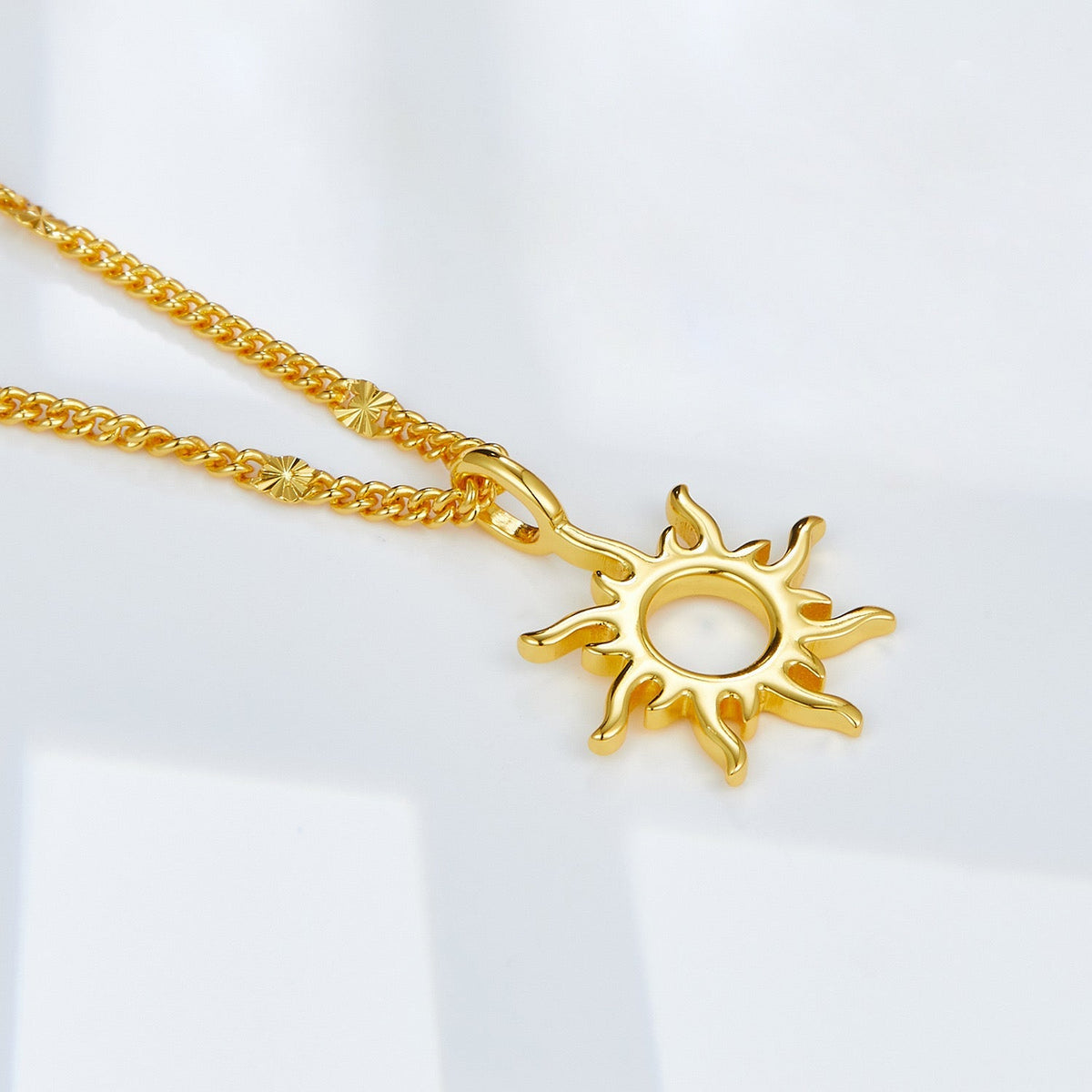 Close-up of the sunburst Helia pendant in 18ct gold vermeil on a light background
